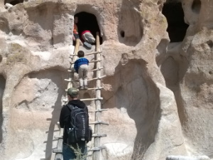 Climbing into a cliff dwelling at Bandelier NM, NM